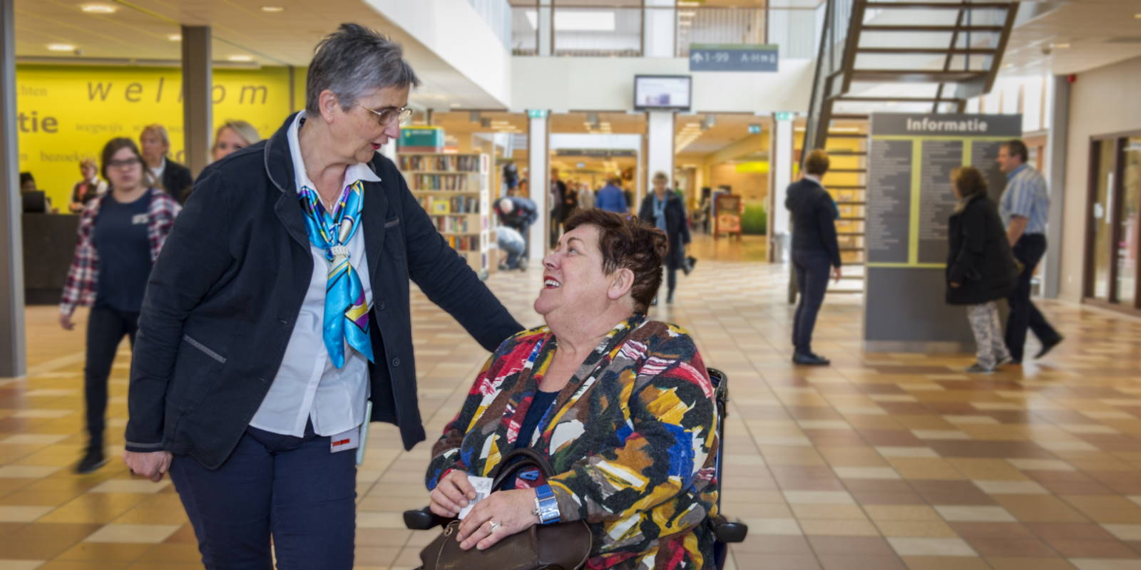 Een gastvrouw in gesprek met een patiënt in de hoofdingang