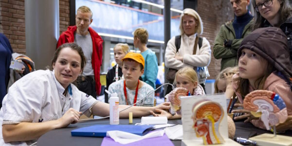 Kinderen en ouders zien een zenuwonderzoek-demonstratie bij het Weekend van de Wetenschap 2024.