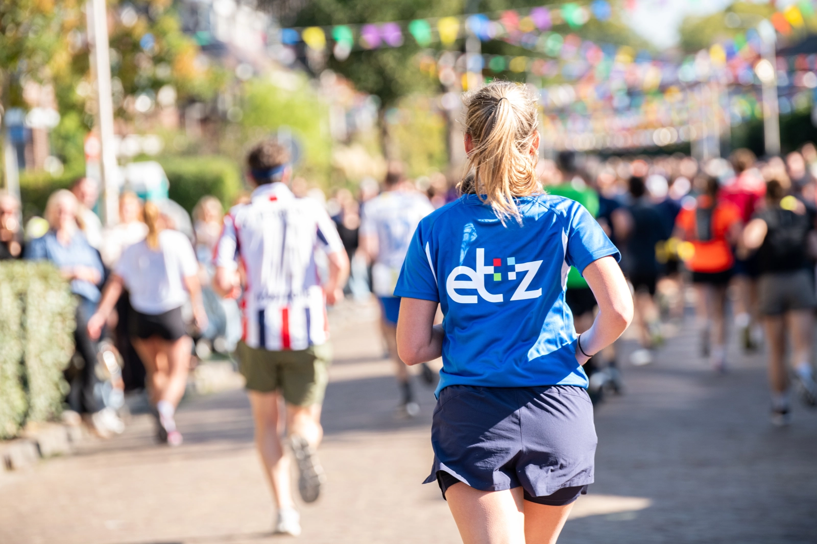 Een hardloper in actie. Ze draagt een blauw shirt met daarop het logo van het ETZ