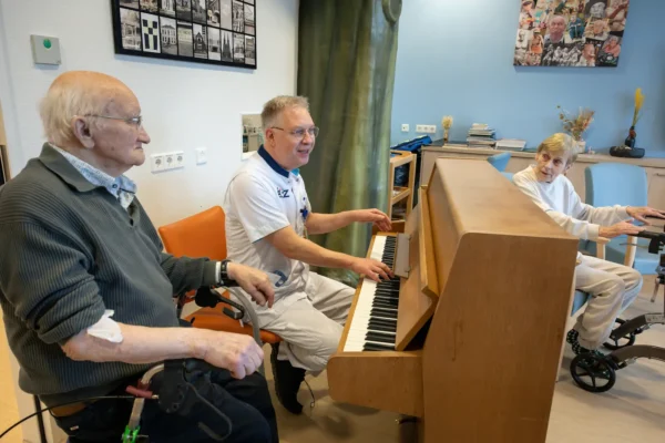 Verpleegkundige achter de piano op de Geriatrie afdeling.