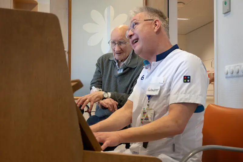 Verpleegkundige achter de piano op de Geriatrie afdeling.