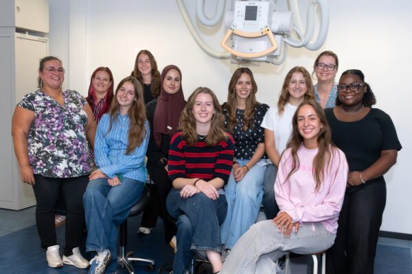 Studenten, begeleiders en docent poseren onder een röntgenapparaat